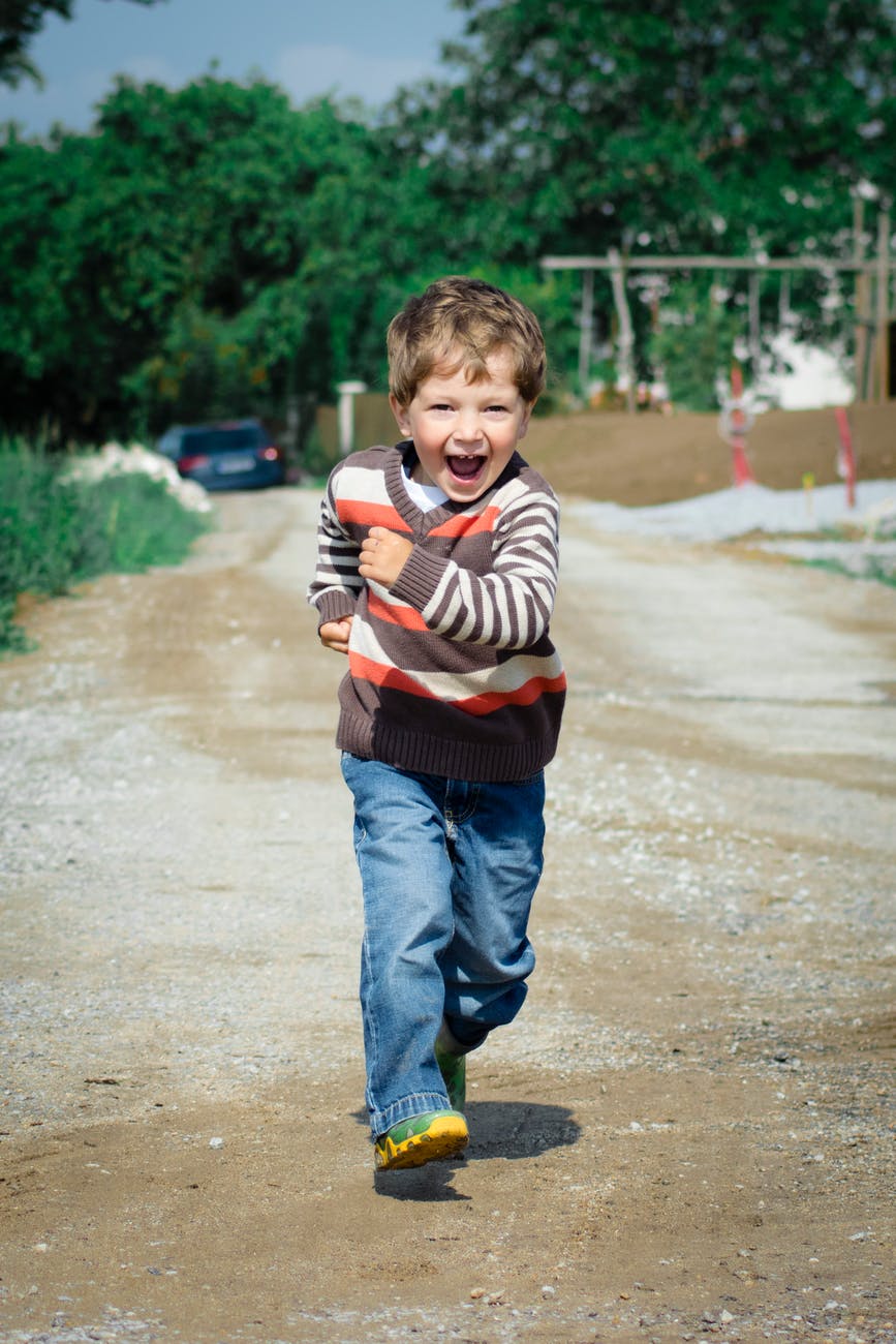 boy wearing red brown and white stripe sweater running photo
